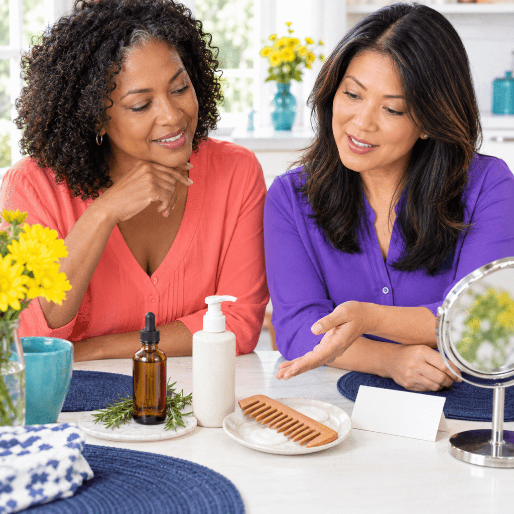 Two smiling midlife women reviewing rosemary scalp oil, minoxidil, gentle hair care and medical evaluation options.